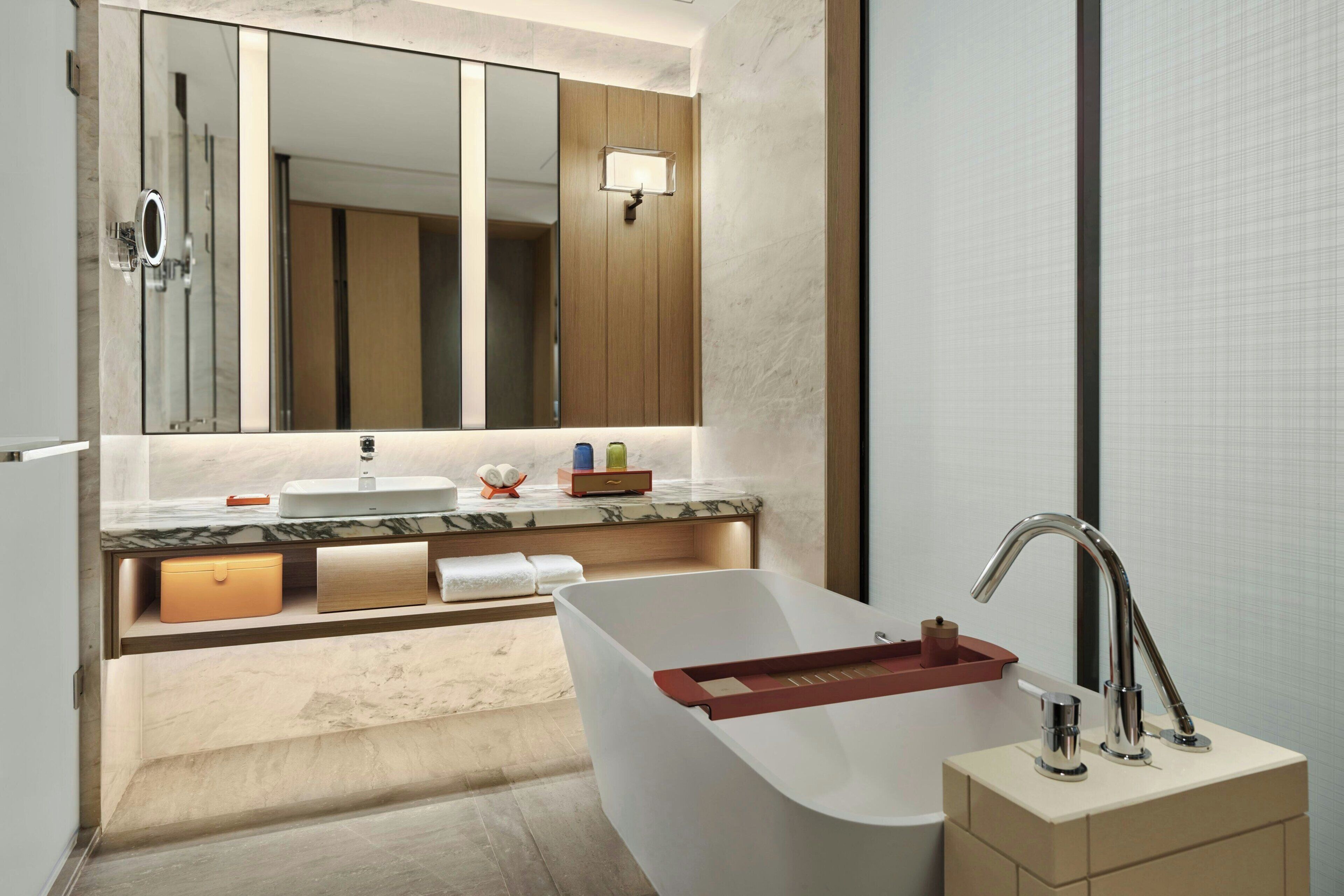 A modern bathroom with a freestanding bathtub, a large mirror, and a vanity with a sink.