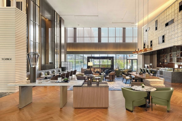 A spacious lounge area with seating arrangements, a bar, and large windows offering views.