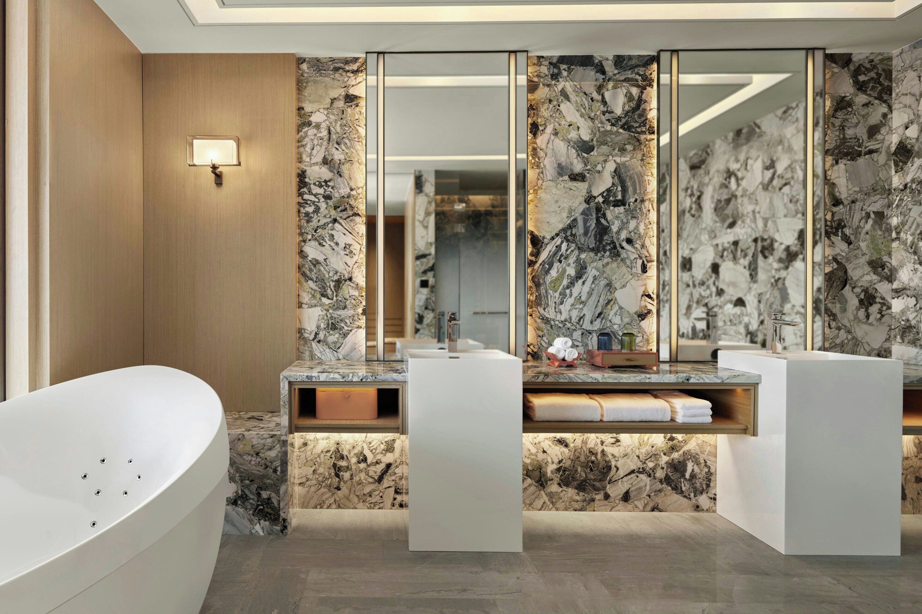 A modern bathroom with a freestanding bathtub, a vanity with a marble countertop, and a large mirror.