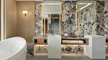 A modern bathroom with a freestanding bathtub, a vanity with a marble countertop, and a large mirror.