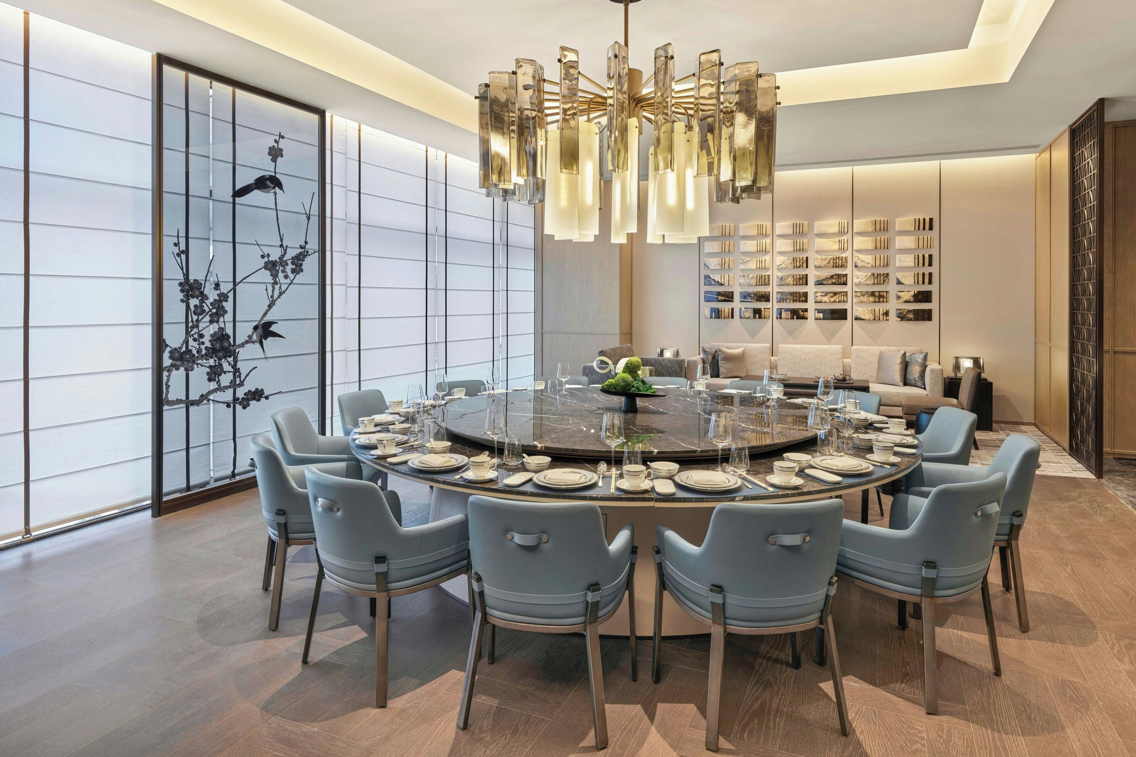 A modern dining room with a round table set for six, surrounded by six chairs.