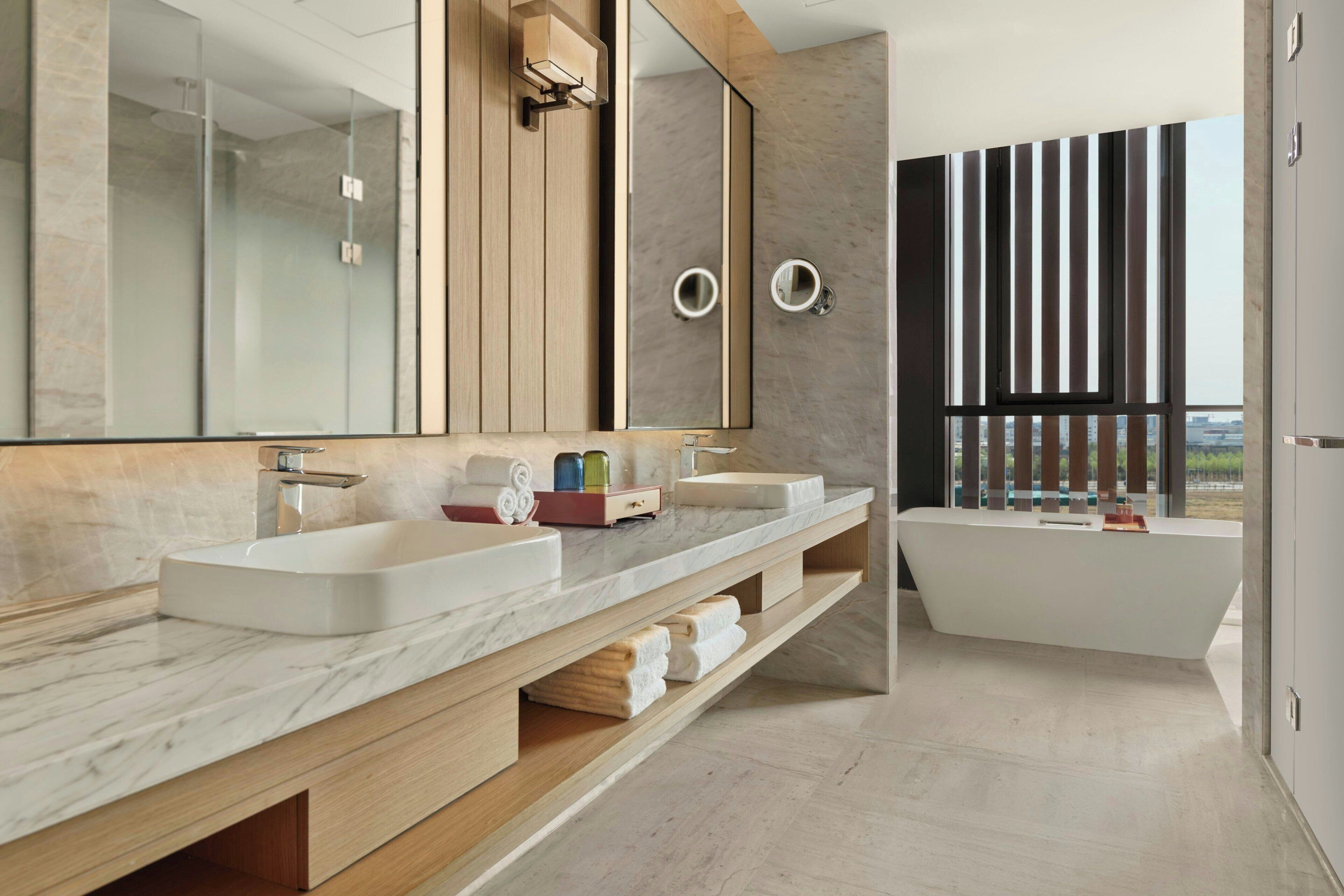 Une salle de bain moderne avec deux lavabos, un grand miroir et une baignoire.
