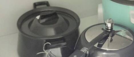 A kitchen with a stove, a pot, and a kettle.