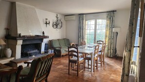 A dining area with a fireplace, a table, chairs, and a window with curtains. - Country House (Saint-Drézéry)