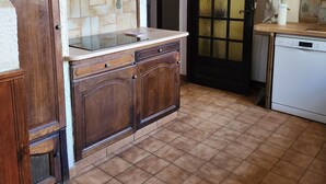 A kitchen with wooden cabinets, a tiled backsplash, a white countertop, and a white dishwasher. - Country House (Saint-Drézéry)