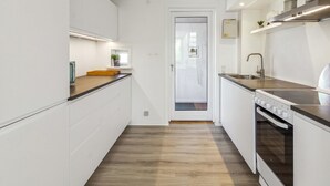 Et moderne køkken med hvide skabe, en træbordplade og en indbygget ovn.