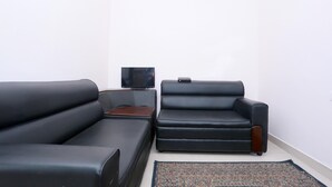 A living room with a sofa, a chair, a small table, and a television. - Classic Ambalathara Eastfort (Thiruvananthapuram)
