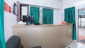 A reception area with a desk, computer, telephone, and green curtains. - Classic Ambalathara Eastfort (Thiruvananthapuram)