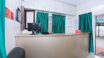 A reception area with a desk, computer, telephone, and green curtains.