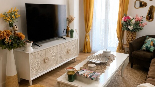 Una sala de estar con televisor, mueble blanco, sofá y una mesa de centro.