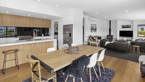 Une cuisine moderne dotée d’un îlot central, un coin repas avec une table en bois et un salon avec un canapé et un téléviseur.
