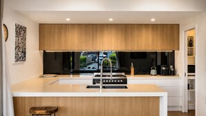 Une cuisine moderne dotée d’un îlot central, de meubles en bois et d’un four encastré.