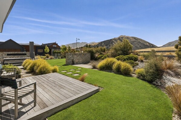 A well-maintained garden with a wooden deck, stone walls, and a variety of shrubs.