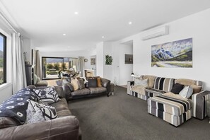 Ein modernes Wohnzimmer mit einer Eckcouch, einer gestreiften Couch und einem Essbereich mit Tisch und Stühlen.