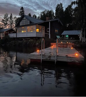 A waterfront property with a dock, a house with a balcony, and a small shed.