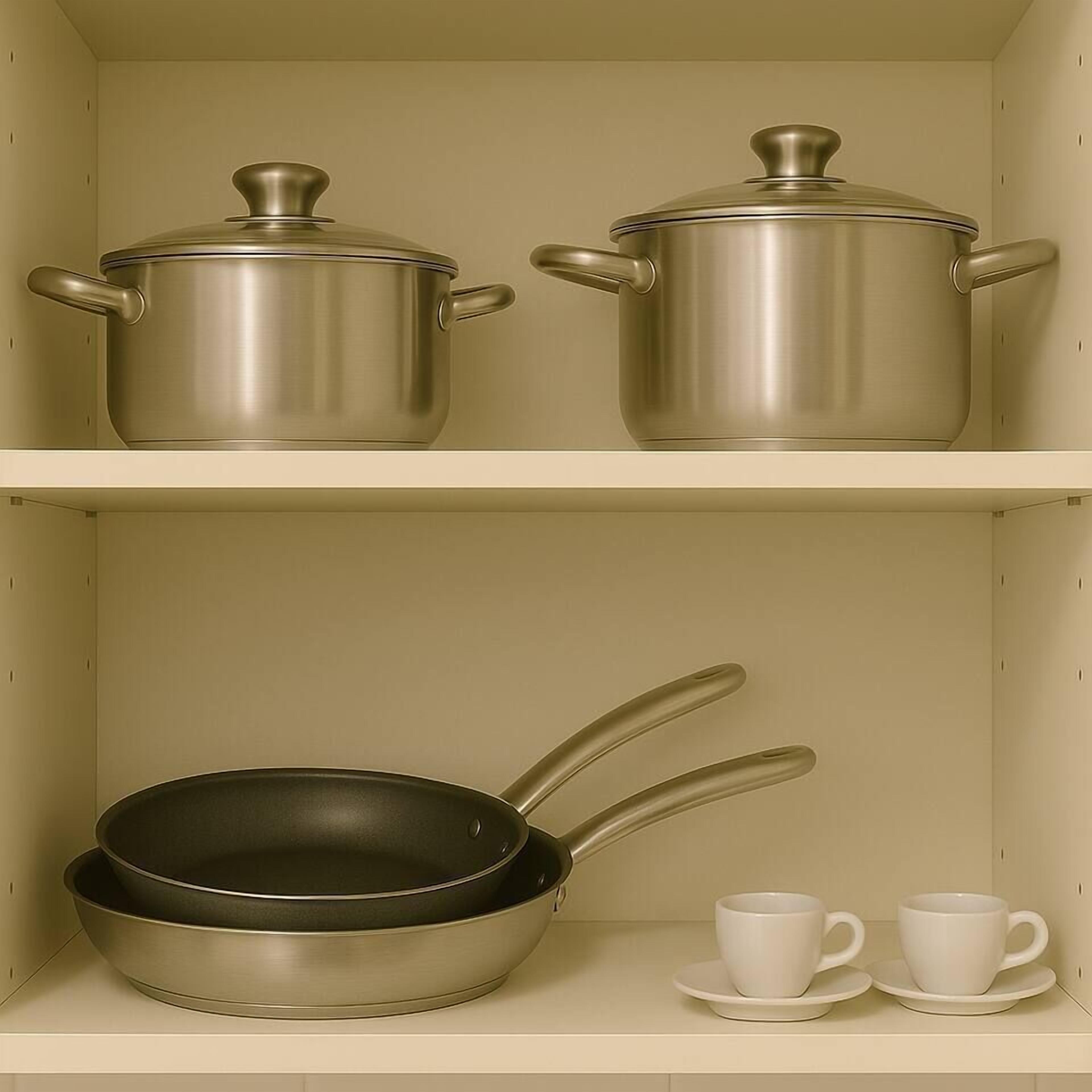 Une cuisine équipée d’ustensiles de cuisine en acier inoxydable, notamment des casseroles et une poêle, et de deux tasses blanches posées sur une étagère.