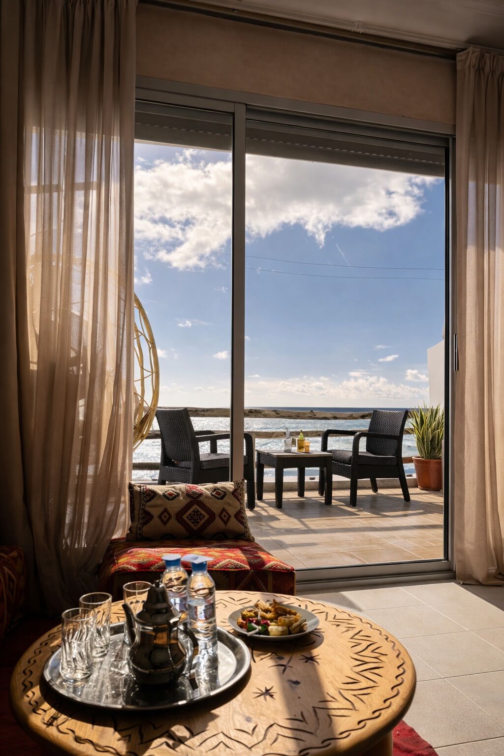 Un balcon avec une table dressée pour le dîner, un canapé et une vue sur la mer.