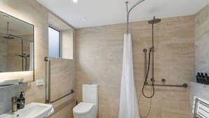 Een moderne badkamer met een douche, toilet, wastafel en een grote spiegel.