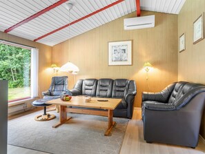 Een moderne woonkamer met lederen banken, een houten salontafel en een groot raam met uitzicht op groen.