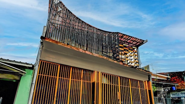 A building with a sloped roof, a large open garage door, and a metal fence. - Cozy Double Escape W/ Free Wifi and Parking (Surabaya)