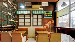 A café with wooden tables and chairs, a green and white striped awning, and a fruit painting on the wall. - Cozy Double Escape W/ Free Wifi and Parking (Surabaya)