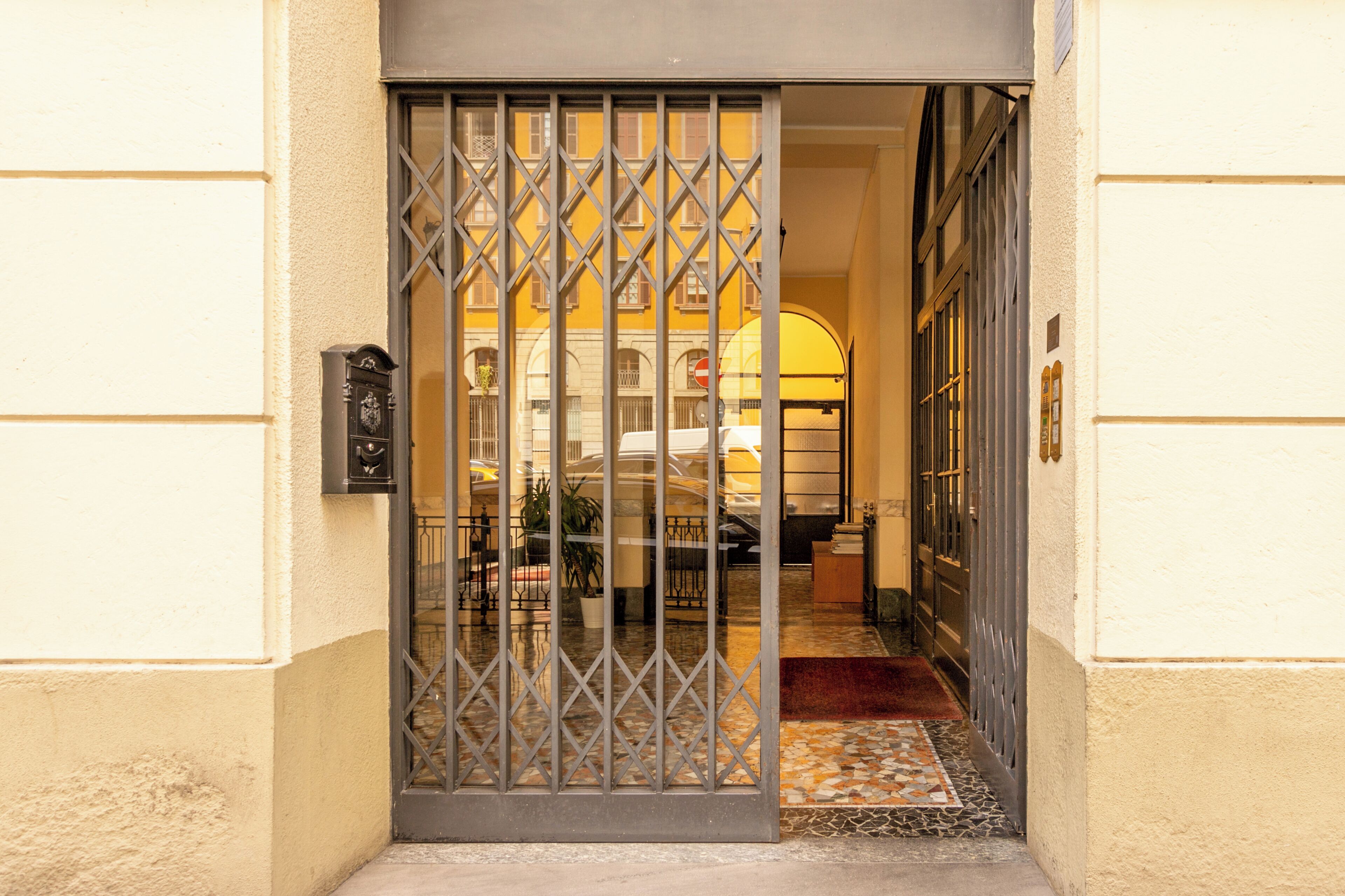 L'ingresso di un hotel con un cancello in metallo, una reception e un pavimento piastrellato.