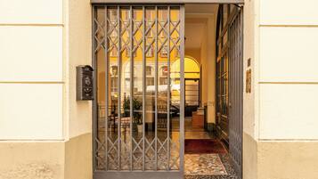 L'ingresso di un hotel con un cancello in metallo, una reception e un pavimento piastrellato.