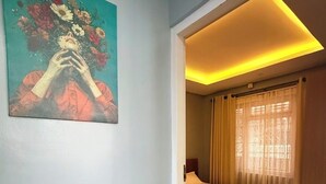 Hotellihuone, jossa on sänky, taulu seinällä ja kattovalaisin.