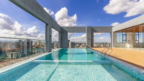Una piscina sul tetto con vista sulla città, cielo sereno e architettura moderna.