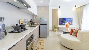 Una cucina moderna con frigorifero, fornello e lavello. C'è un'area pranzo con divano e televisione.