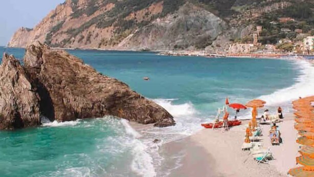 A beach with rocky formations, clear blue water, and a hilly backdrop. - Cozy and modern apartment (Pagliadiccio)