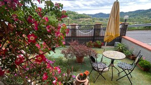 A patio with a table and chairs, surrounded by potted plants and a view of the countryside. - Cozy and modern apartment (Pagliadiccio)