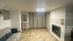 A living room with a sofa, a fireplace, and a tiled floor. - Cozy and modern apartment (Pagliadiccio)