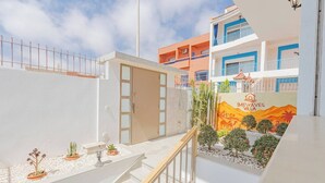 A hotel courtyard with a staircase, potted plants, and a mural of a desert landscape. - Chic Boho Paradise w/ Parking, Rooftop & Workspace (Imi Ouaddar)