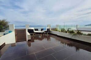 A rooftop terrace with a pool, seating area, and a view of the sea.