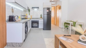 A modern kitchen with a built-in oven, a refrigerator, and a dining area with a table and chairs. - Couple Haven•Workspace & WiFi 200Mb/s•Free Parking (Imi Ouaddar)