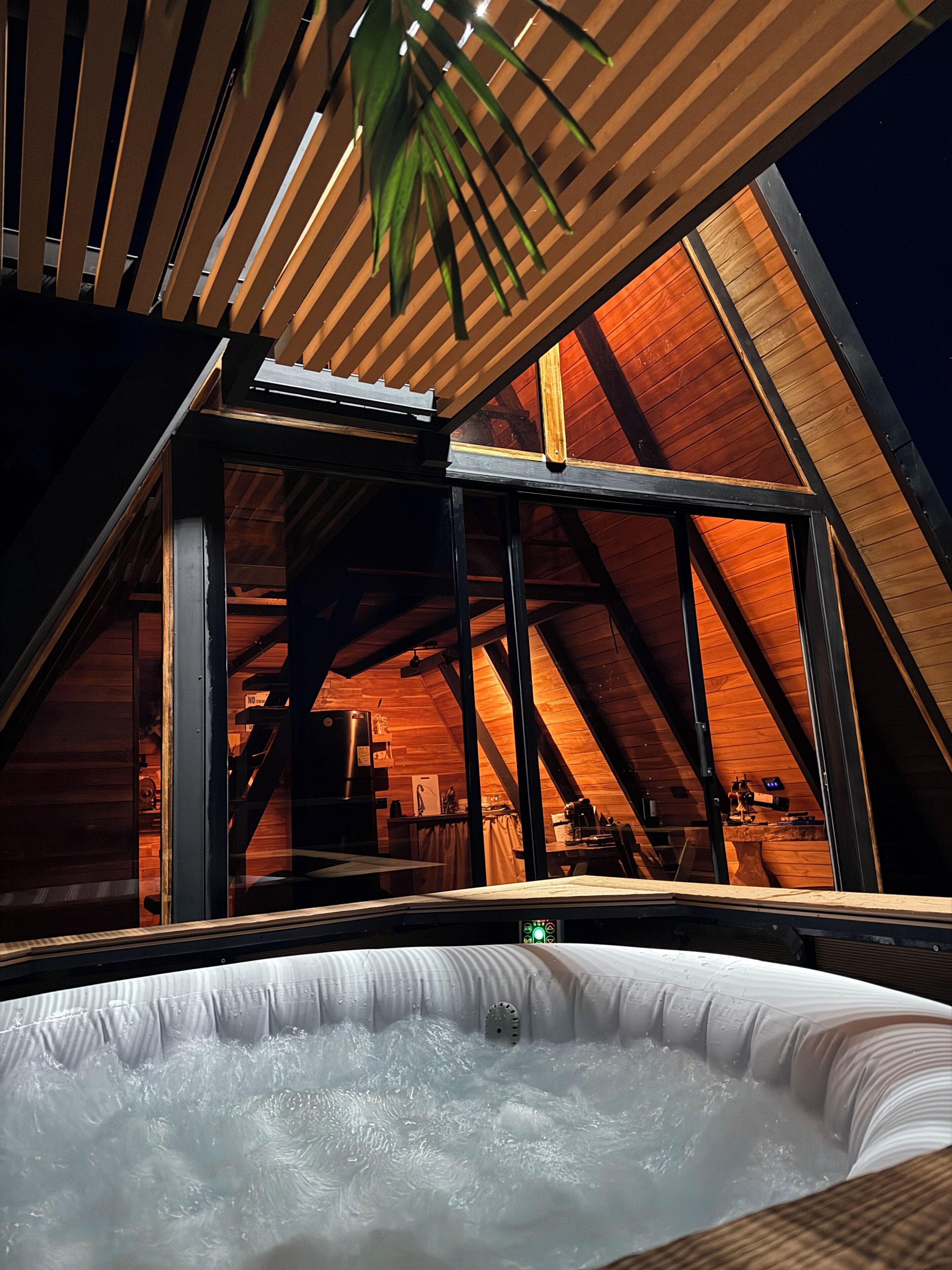 Un jacuzzi en un cuarto ático de madera con techo inclinado y ventanas amplias.