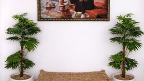 A room with a framed painting, a bench, and two potted plants. - Luxury Berber Chic•3mn to Beach•Rooftop•Balcony•AC (Imi Ouaddar)