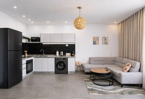 Una cocina moderna con lavadora, un sofá gris y una mesa de centro redonda.