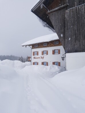 Um edifício coberto de neve com uma placa que diz 'Maurer Hof'.