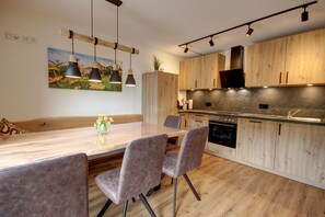 Eine moderne Küche mit Holzschränken, einer Marmorarbeitsplatte und Pendelleuchten.