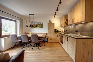 A modern kitchen with wooden cabinets, a dining area with chairs, and a large window. - "Zuhaus" Vacation Rental on the 1st Floor, 70 square meters (Siegsdorf)