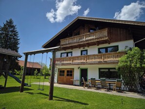 Ein zweistöckiges Gebäude mit Balkon, Schaukel und Sitzgelegenheit im Freien.