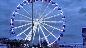 Ein großes Riesenrad mit Gondeln, einer zentralen Beleuchtung und einer umlaufenden Konstruktion.