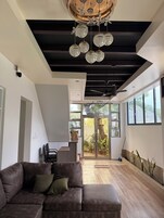 Um interior moderno com sofá seccional, ventoinha no teto e janelas amplas.