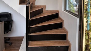 A staircase with wooden steps and black railings, leading to an upper floor.