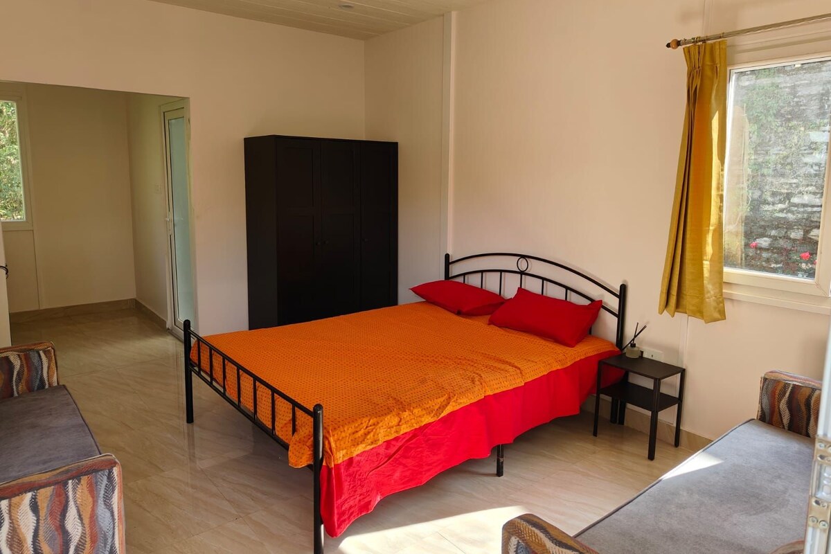Una cama individual con estructura metálica, una mesita de noche, un armario y una ventana con cortinas.