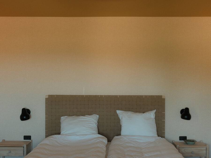 A double bed with a headboard, two bedside tables, and wall-mounted lamps.