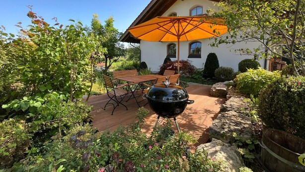 A patio with a table and chairs, a barbecue grill, and an umbrella. - Vacation home with 3 separate bedrooms, 160 square meters (Truchtlaching)