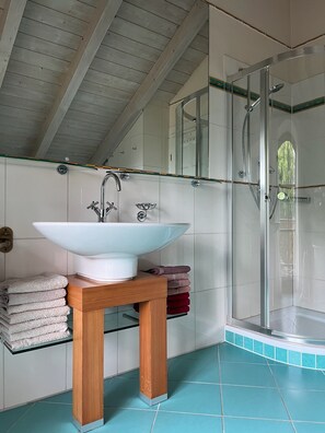 A bathroom with a large white sink, a wooden stool, a glass shower enclosure, and a tiled floor. - Vacation home with 3 separate bedrooms, 160 square meters (Truchtlaching)
